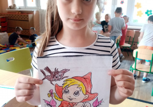 Dziewczynka prezentuje pomalowaną przez siebie kolorowankę.